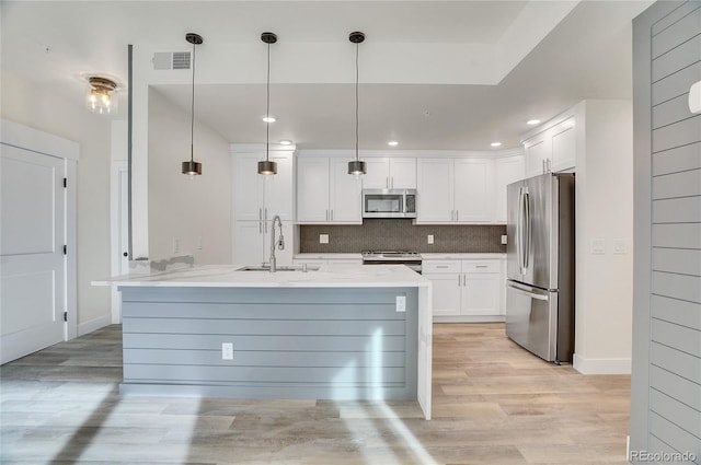 kitchen featuring light hardwood / wood-style flooring, tasteful backsplash, hanging light fixtures, white cabinetry, and appliances with stainless steel finishes