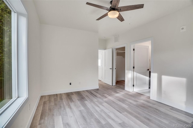 unfurnished bedroom featuring a spacious closet, ceiling fan, and light hardwood / wood-style flooring