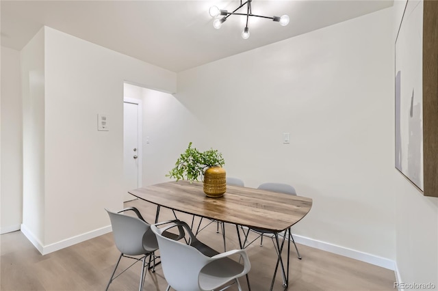 dining space with light wood-style flooring, baseboards, and an inviting chandelier