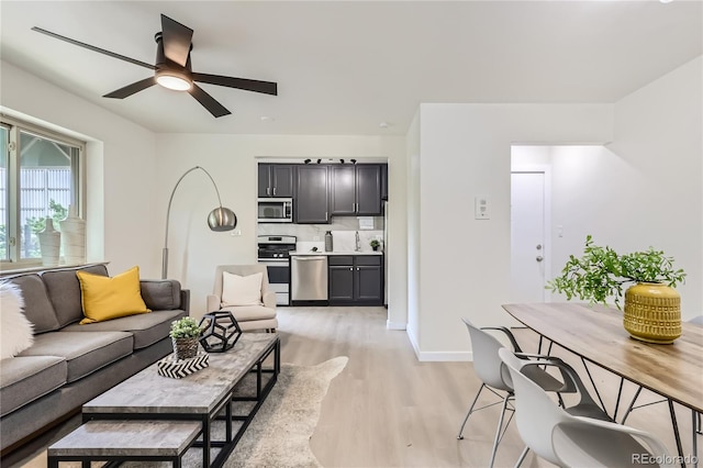 living area with baseboards, light wood-type flooring, and ceiling fan