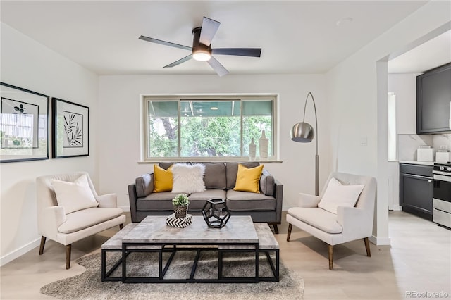 living room featuring baseboards, light wood-style floors, and ceiling fan