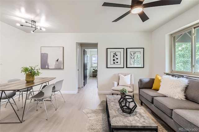 living area featuring baseboards, light wood-style floors, and a ceiling fan