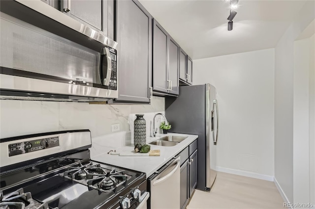 kitchen with baseboards, a sink, stainless steel appliances, light countertops, and backsplash