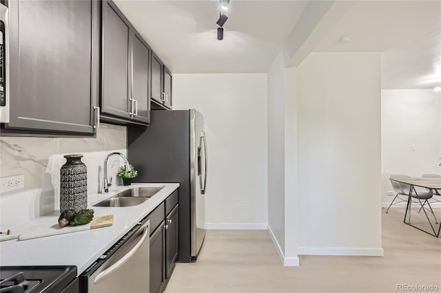 kitchen featuring a sink, light countertops, decorative backsplash, light wood-style flooring, and stainless steel dishwasher