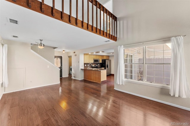 unfurnished living room featuring ceiling fan, dark hardwood / wood-style floors, and washer / dryer