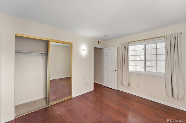 unfurnished bedroom featuring a closet and dark wood-type flooring