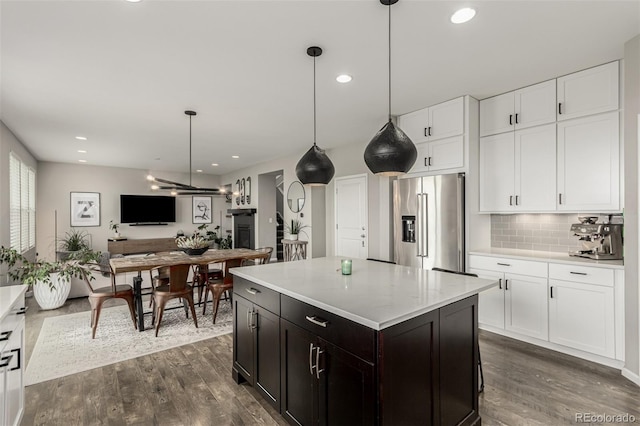 3168 Raintree Ln, Dacono, CO 80514 - kitchen featuring high quality fridge, white cabinets, dark wood finished floors, tasteful backsplash, and open floor plan