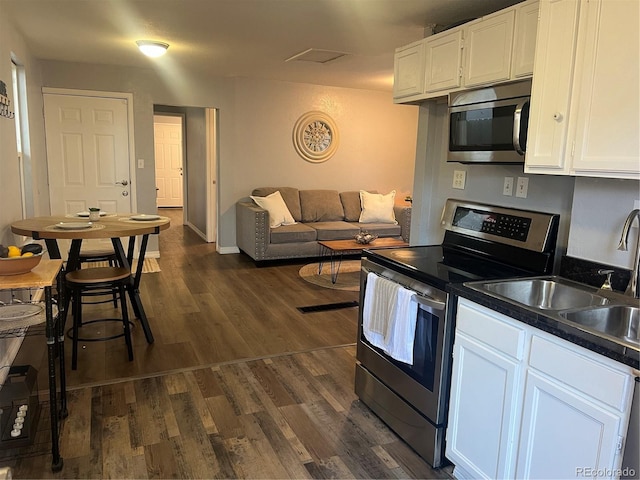 kitchen featuring dark hardwood / wood-style floors, appliances with stainless steel finishes, white cabinetry, and sink