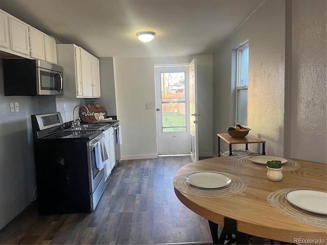 kitchen with dark wood-type flooring, sink, stainless steel appliances, and white cabinetry