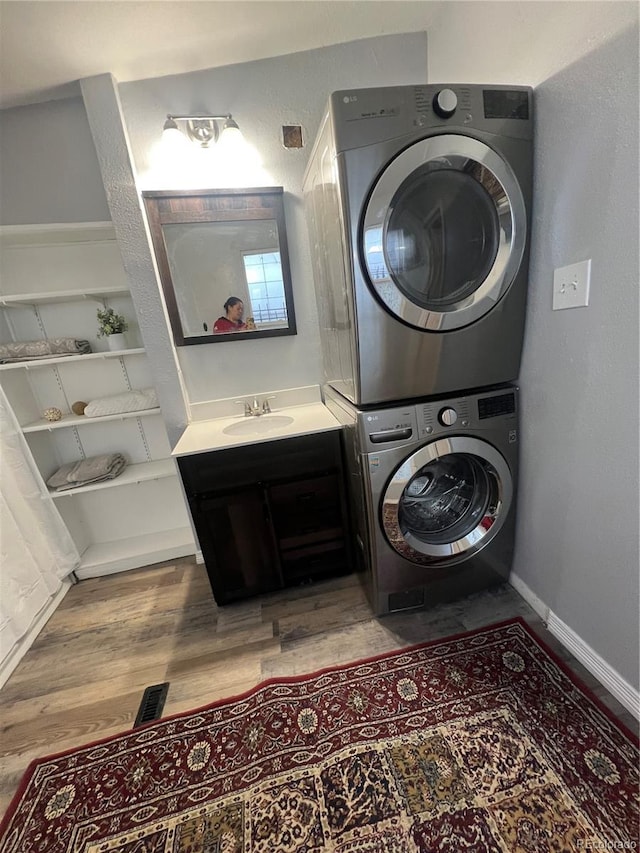 laundry room with stacked washer and dryer, sink, and hardwood / wood-style flooring