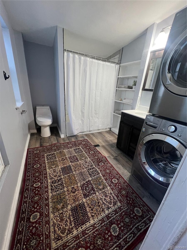 bathroom with stacked washer and dryer, toilet, hardwood / wood-style floors, and vanity