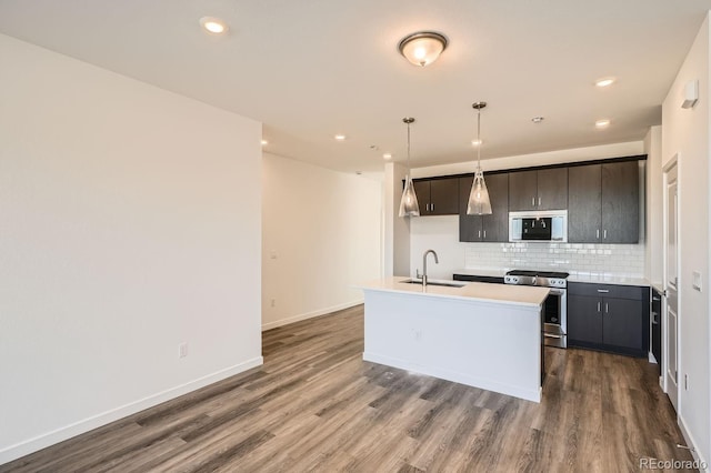 kitchen featuring stainless steel gas range oven, a sink, light countertops, built in microwave, and pendant lighting