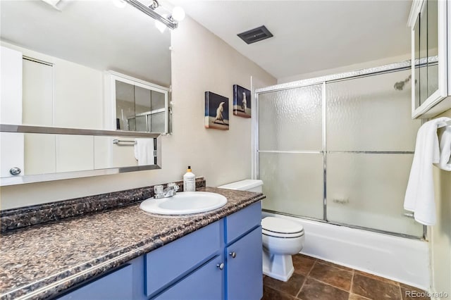 full bathroom featuring vanity, combined bath / shower with glass door, and toilet