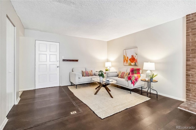 living room featuring dark wood finished floors, a textured ceiling, and baseboards