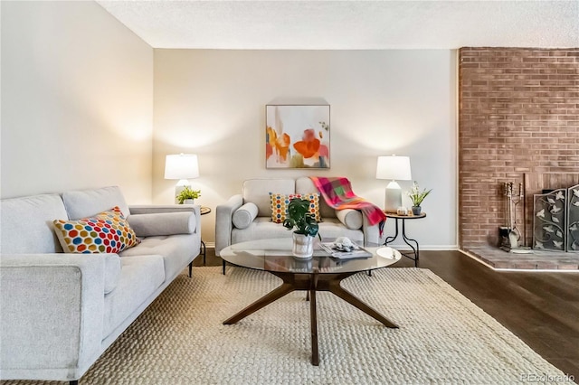 living room featuring dark wood finished floors, a fireplace, a textured ceiling, and baseboards