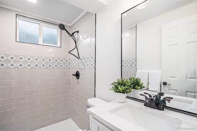 bathroom with a tile shower, vanity, and ornamental molding