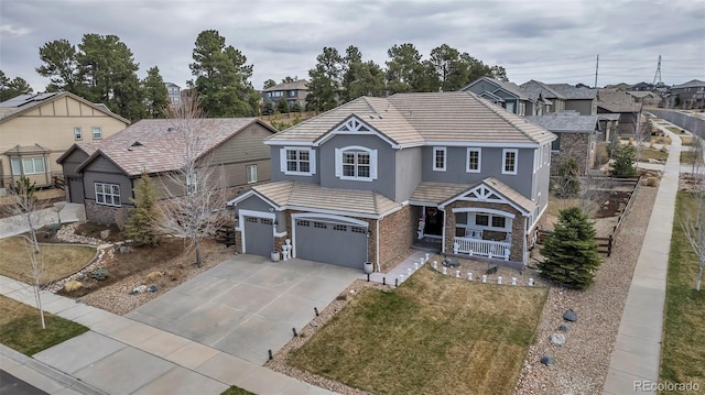 craftsman inspired home featuring concrete driveway, stone siding, an attached garage, a porch, and a residential view