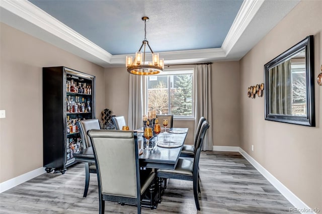 dining area featuring crown molding, a chandelier, and a raised ceiling