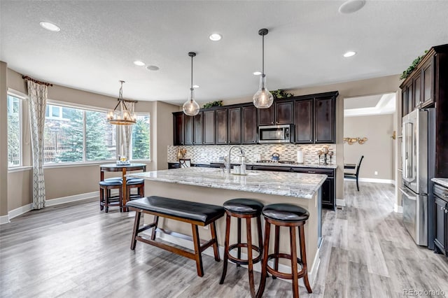 kitchen featuring dark brown cabinets, baseboards, backsplash, and appliances with stainless steel finishes
