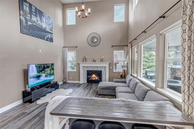 living room featuring baseboards, wood finished floors, a towering ceiling, and a tile fireplace
