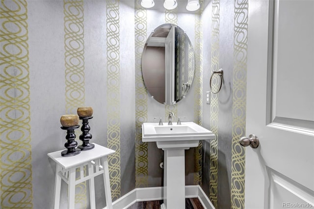 bathroom featuring baseboards, wood finished floors, and wallpapered walls