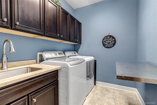washroom with cabinet space, washing machine and clothes dryer, baseboards, and a sink