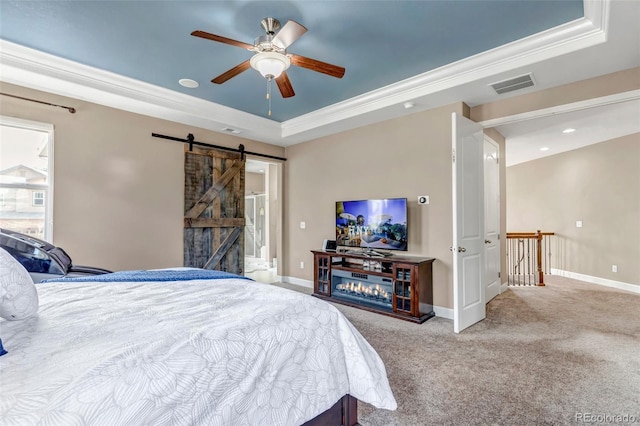 bedroom featuring a barn door, a raised ceiling, visible vents, carpet floors, and baseboards