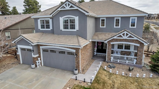view of front of house featuring stone siding, covered porch, and stucco siding