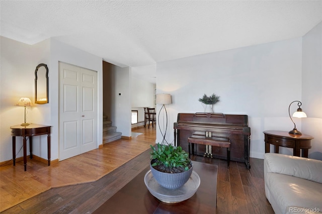 living room with dark wood-type flooring, a textured ceiling, and baseboards