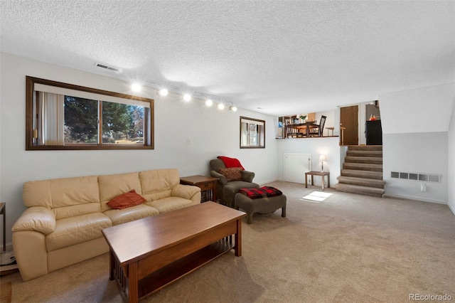 living room featuring visible vents, stairway, carpet flooring, and a textured ceiling