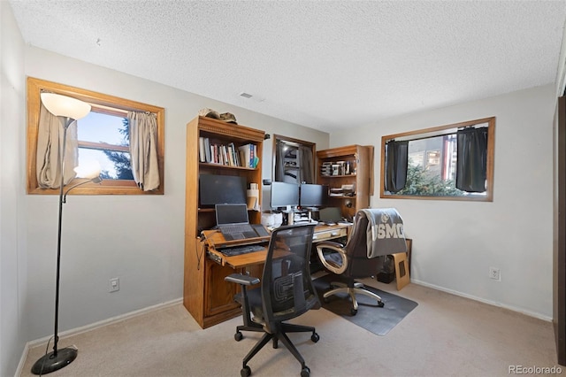 office space with light carpet, a textured ceiling, and baseboards