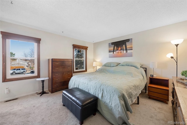 bedroom with light carpet, baseboards, visible vents, and a textured ceiling