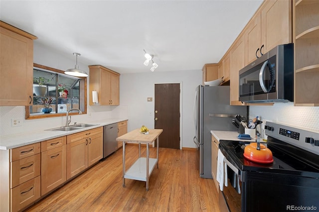 kitchen featuring stainless steel appliances, light countertops, a sink, and light brown cabinets