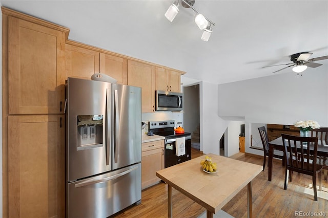 kitchen with light brown cabinets, stainless steel appliances, a ceiling fan, light countertops, and light wood finished floors