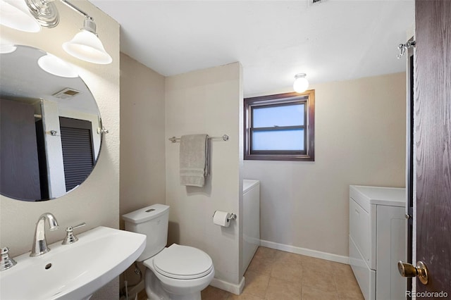 bathroom featuring toilet, a sink, visible vents, baseboards, and tile patterned floors