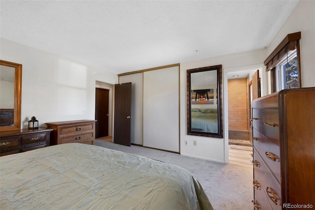 bedroom with a closet, light carpet, connected bathroom, and a textured ceiling