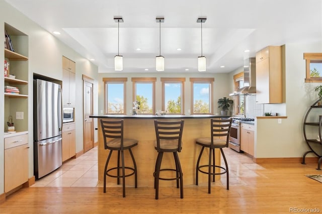 4305 Easley Rd, Golden, CO 80403 - kitchen featuring a breakfast bar, a tray ceiling, wall chimney range hood, and stainless steel appliances