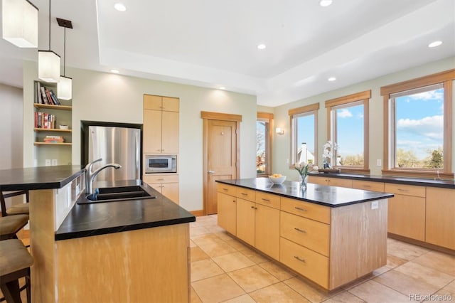4305 Easley Rd, Golden, CO 80403 - kitchen with light brown cabinetry, a sink, freestanding refrigerator, white microwave, and a center island with sink