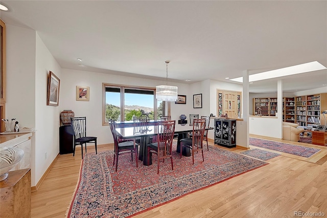 dining area with a chandelier, light wood-type flooring, and baseboards