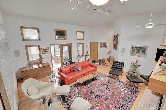 living room featuring rail lighting, a ceiling fan, high vaulted ceiling, and wood finished floors