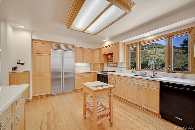 kitchen featuring gas range oven, stainless steel built in fridge, a sink, light brown cabinets, and dishwasher