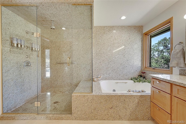 bathroom featuring a jetted tub, a shower stall, and vanity