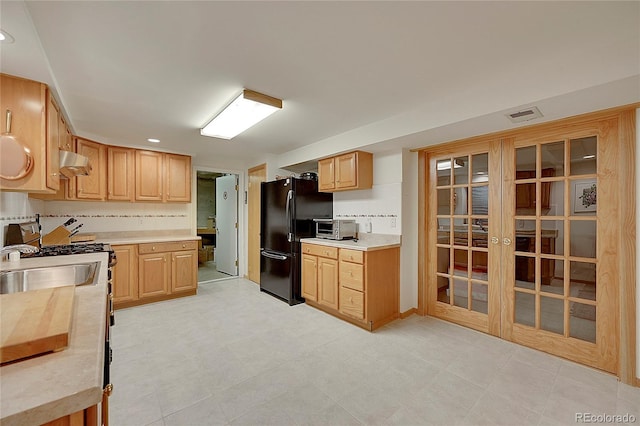 kitchen featuring french doors, light countertops, visible vents, freestanding refrigerator, and under cabinet range hood