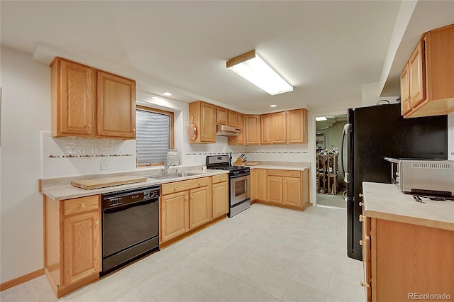 kitchen featuring light countertops, a sink, dishwasher, under cabinet range hood, and stainless steel gas range oven