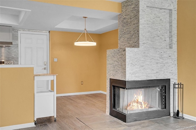 2181 S Troy Way Unit 103, Aurora, CO 80014 - unfurnished living room with a tray ceiling, a multi sided fireplace, and wood finished floors