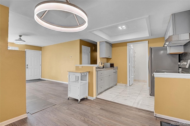 2181 S Troy Way Unit 103, Aurora, CO 80014 - kitchen featuring a raised ceiling, light countertops, stainless steel microwave, and under cabinet range hood