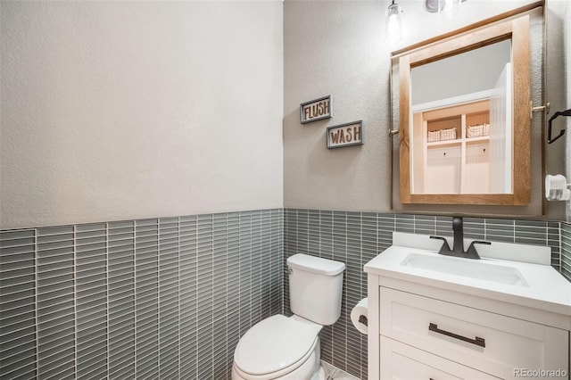 8750 Red Primrose St, Franktown, CO 80116 - bathroom featuring toilet, tile walls, a wainscoted wall, and vanity