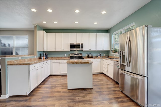 kitchen with kitchen peninsula, white cabinetry, dark wood-type flooring, and stainless steel appliances