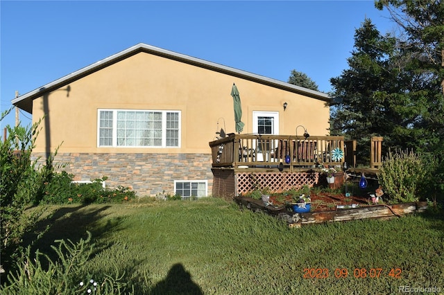 back of house featuring a yard, a wooden deck, and stucco siding