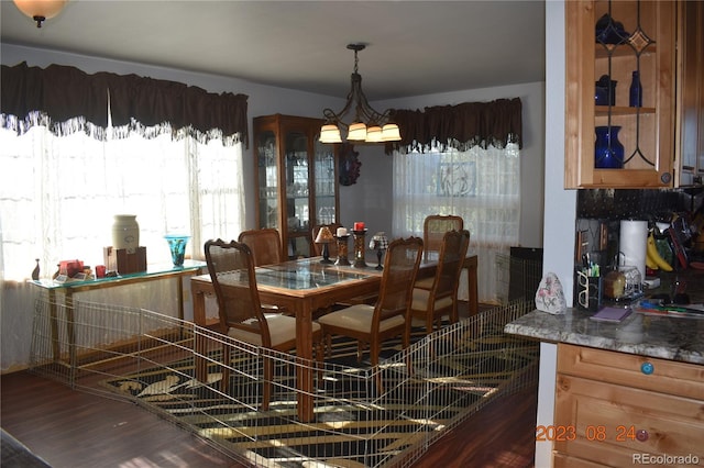 dining space with dark wood finished floors and a notable chandelier